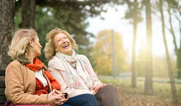 Two senior women sitting outside laughing together.