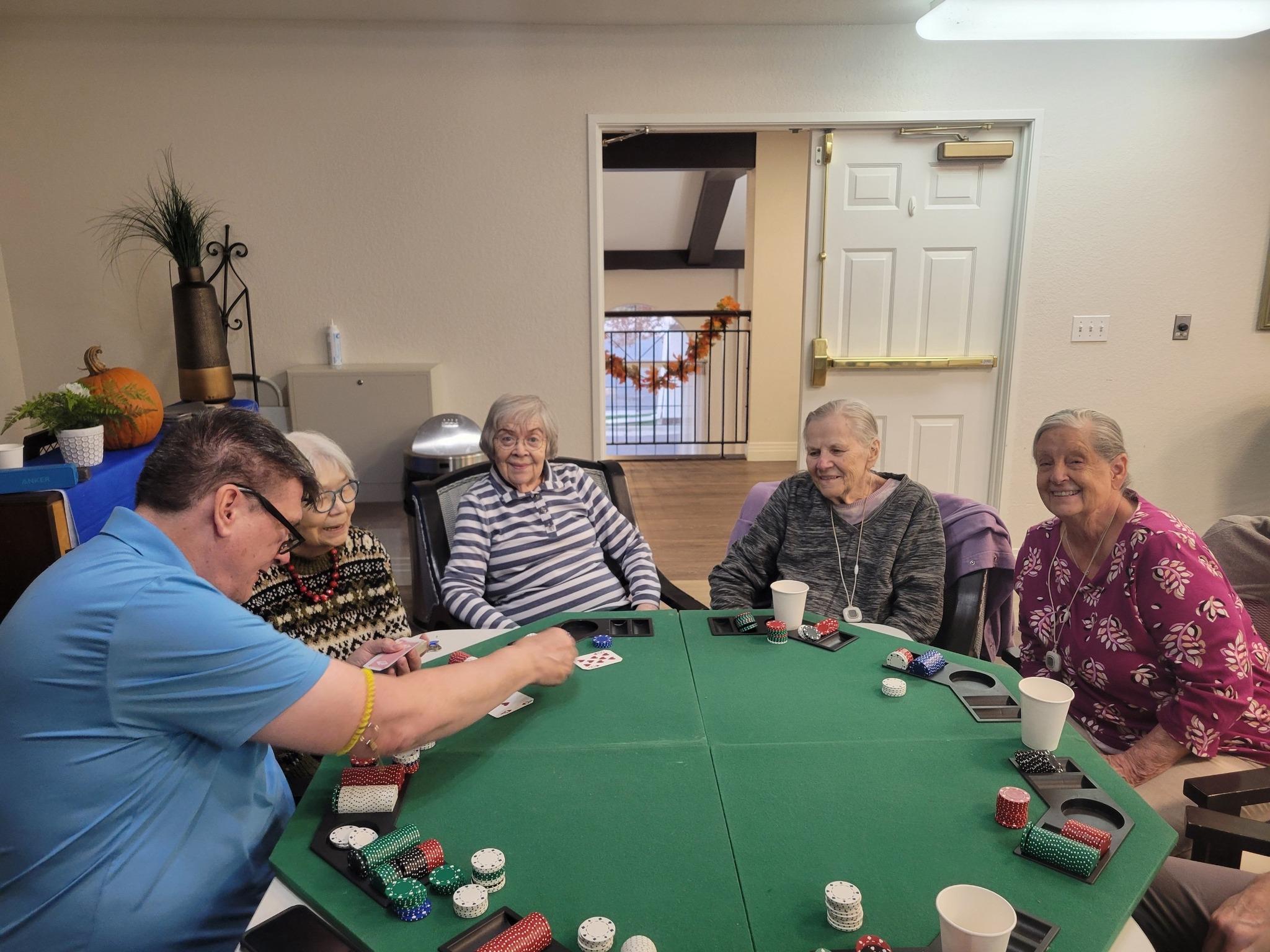 Residents of San Marino Retirement Community sitting at a card table playing poker together.