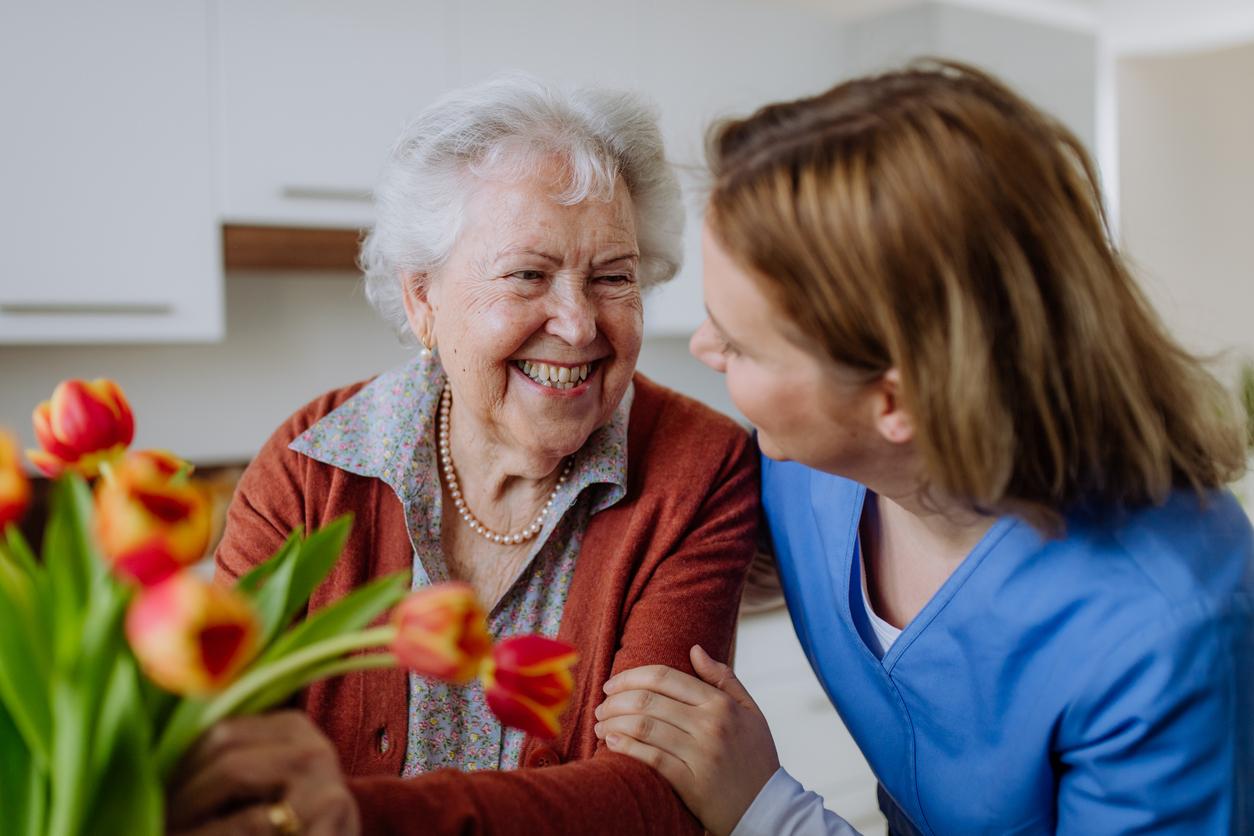 Senior resident in Memory Care with a staff member smiling and arranging a bouquet of flowers Senior resident in Memory Care with a staff member smiling and arranging a bouquet of flowers