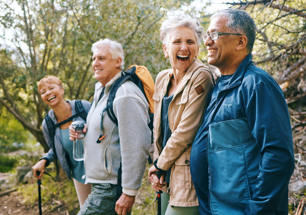 group of seniors smiling and hiking in the woods